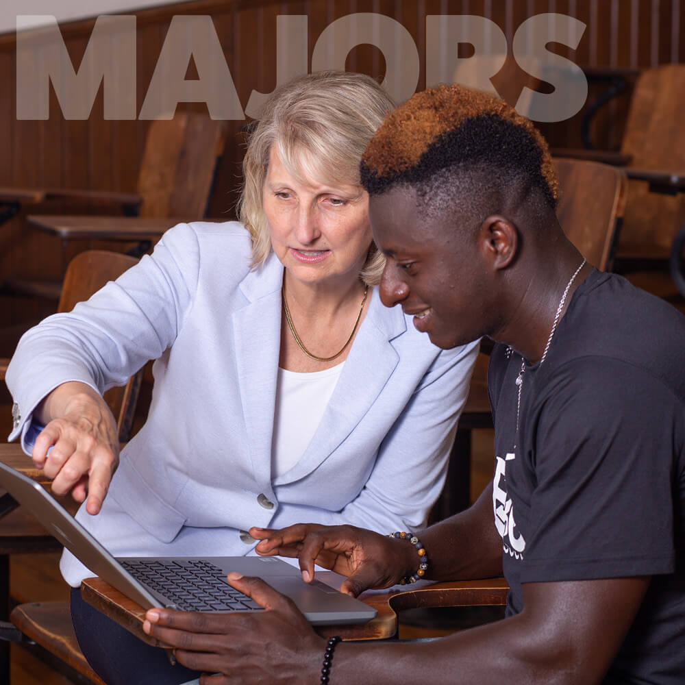 Joyce Hampton, ED.D., Vice President of Academic Affairs counsels student in lecture hall.